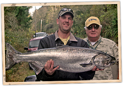 Two men holding a large fish in front of some trees