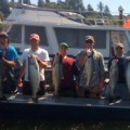 A group of men holding fish on top of a boat.