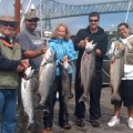 A group of people holding fish on top of a boat.