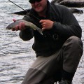 A man holding a fish while standing in the water.