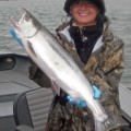 A woman holding a large fish on top of a boat.