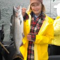 A woman holding a fish on top of a boat.