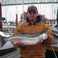 A man holding a fish on top of a boat.