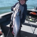 A young boy holding a large fish on the boat.