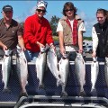 A group of people standing on top of a truck holding fish.