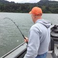 A man in grey hoodie holding a fishing rod.