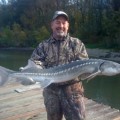 A man holding a large fish on top of a dock.