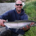 A man holding a fish while sitting on the ground.