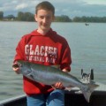 A boy holding a fish on top of a boat.