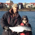 A man and woman holding a fish while standing on the water.