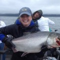 A woman holding a large fish on top of a boat.