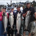 A group of people holding up fish near a boat.