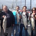 A group of people holding fish on the deck.