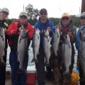 A group of people holding up fish on top of a dock.