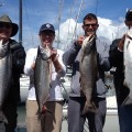 A group of people holding fish on top of a boat.