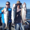 Two people holding up fish on a boat.