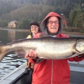 A man and woman holding up a fish on the boat.