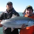 A man and woman holding a fish while standing on the water.