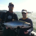 Two men holding a large fish on the water.