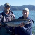 Two men holding a large fish on the water.