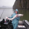 A woman holding a fish while standing on the boat.