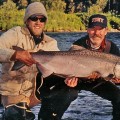 Two men holding a large fish in the water.