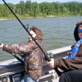 Two people fishing on a boat in the water.