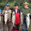 A group of people holding fish on top of a dock.