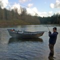 A man fishing in the water next to a boat.