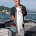 A man holding a fish on top of a boat.