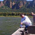 Two men fishing on a boat in the water.