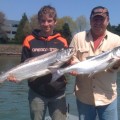 Two men holding up fish in the water.