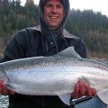 A man holding a large fish while standing on top of a boat.