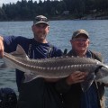 Two men holding a fish while standing on the water.