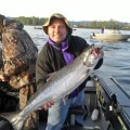 A man holding a fish while standing on top of a boat.