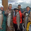 A group of men holding fish on top of a dock.