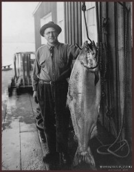 A man standing next to a large fish.