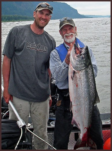 Two men standing next to each other holding a fish.