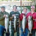 A group of people holding fish on top of a dock.